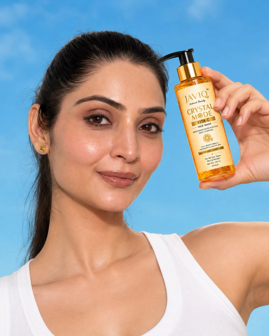 Woman holding JAVIQ Crystal Mode Vita C face wash against a blue sky